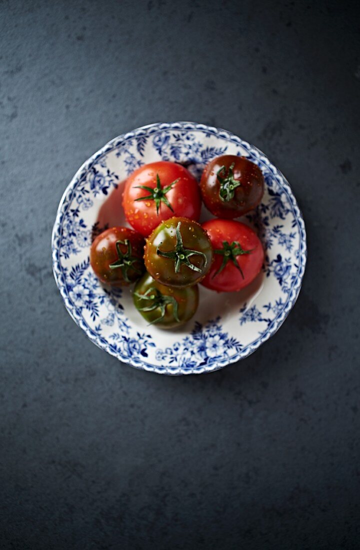 Red and black tomatoes on a plate (seen from above)
