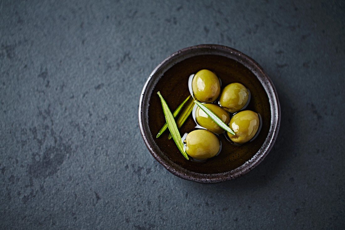 Green olives in oil with rosemary (seen from above)