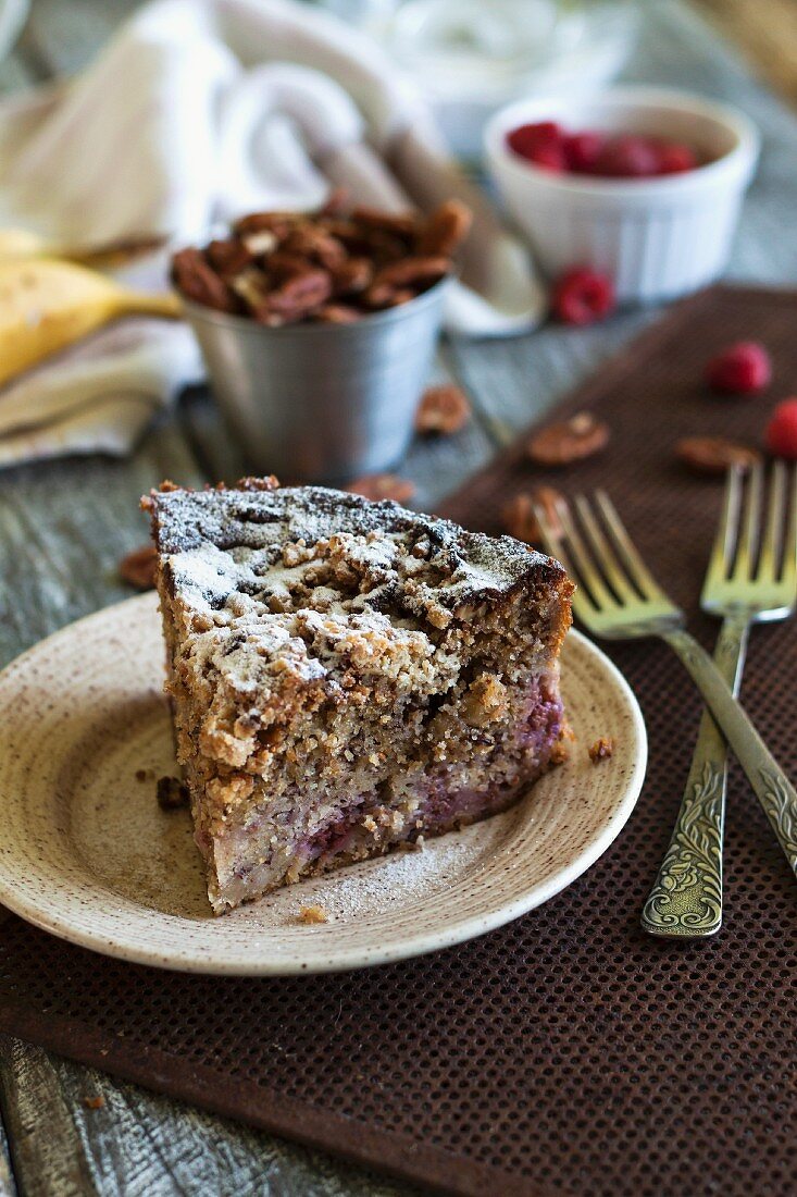 A slice of banana cake with raspberries and pecan nuts