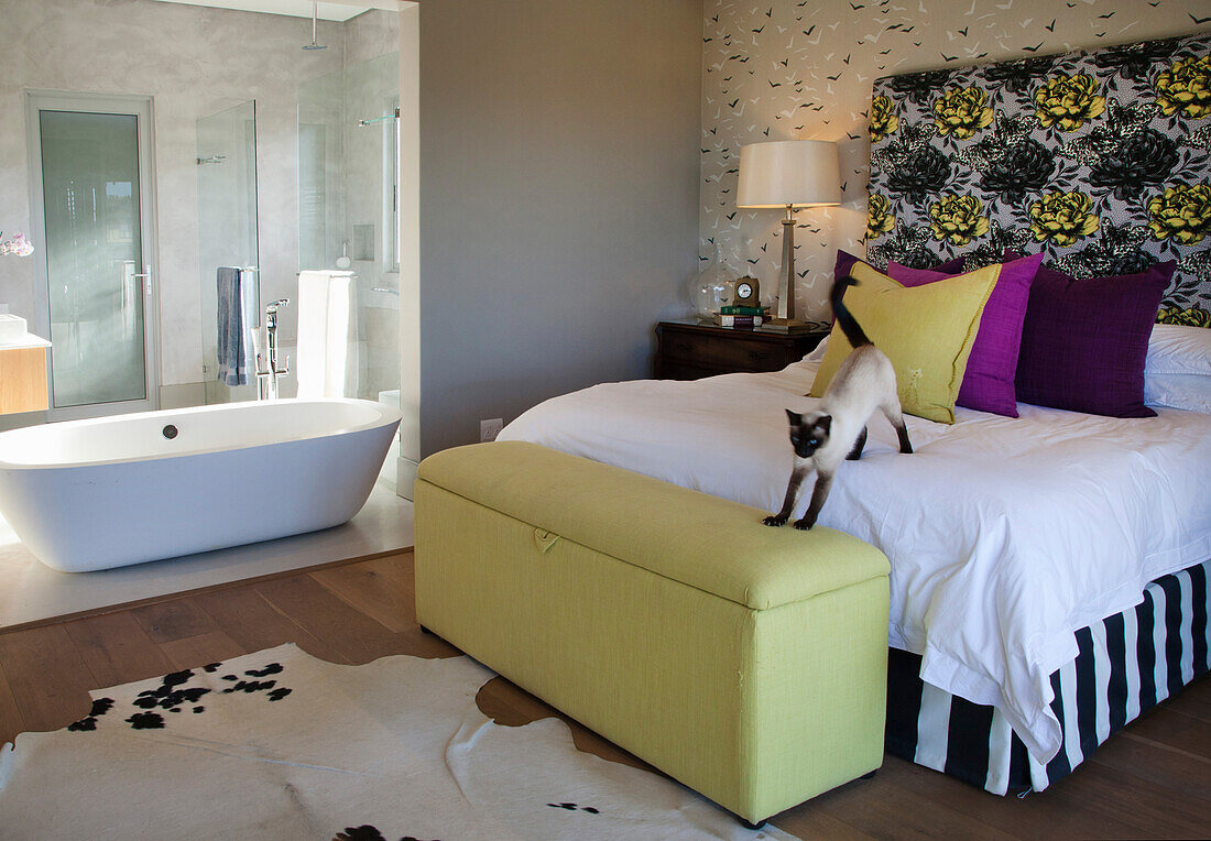 Bedroom with cat on the bed and free-standing bathtub in attached bath