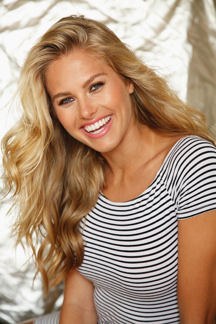A laughing blonde woman wearing a stripped shirt