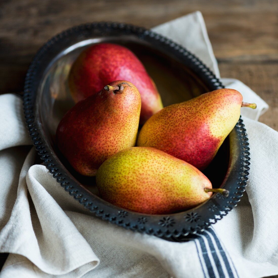 Four pears in a metal bowl
