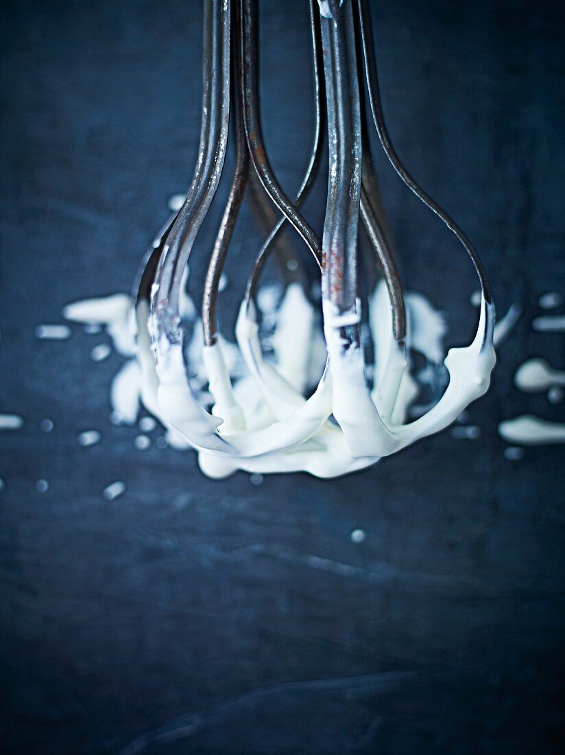 An antique hand whisk with cream on it