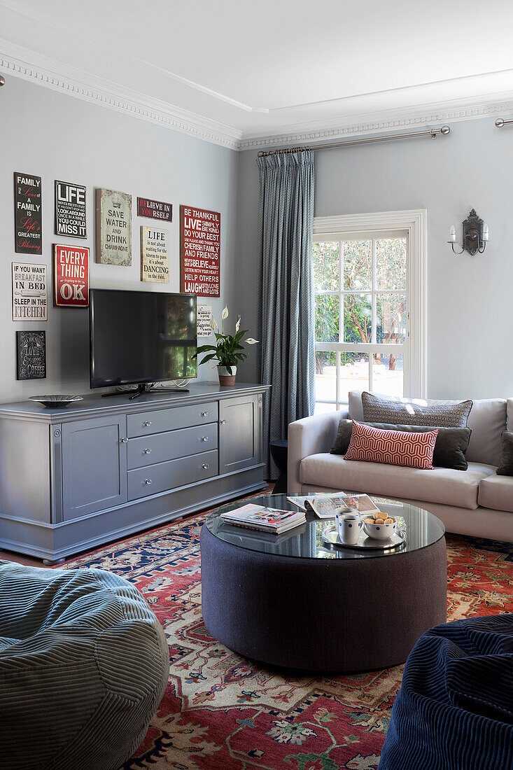 Living room with light grey wall, colourful rug and TV furniture