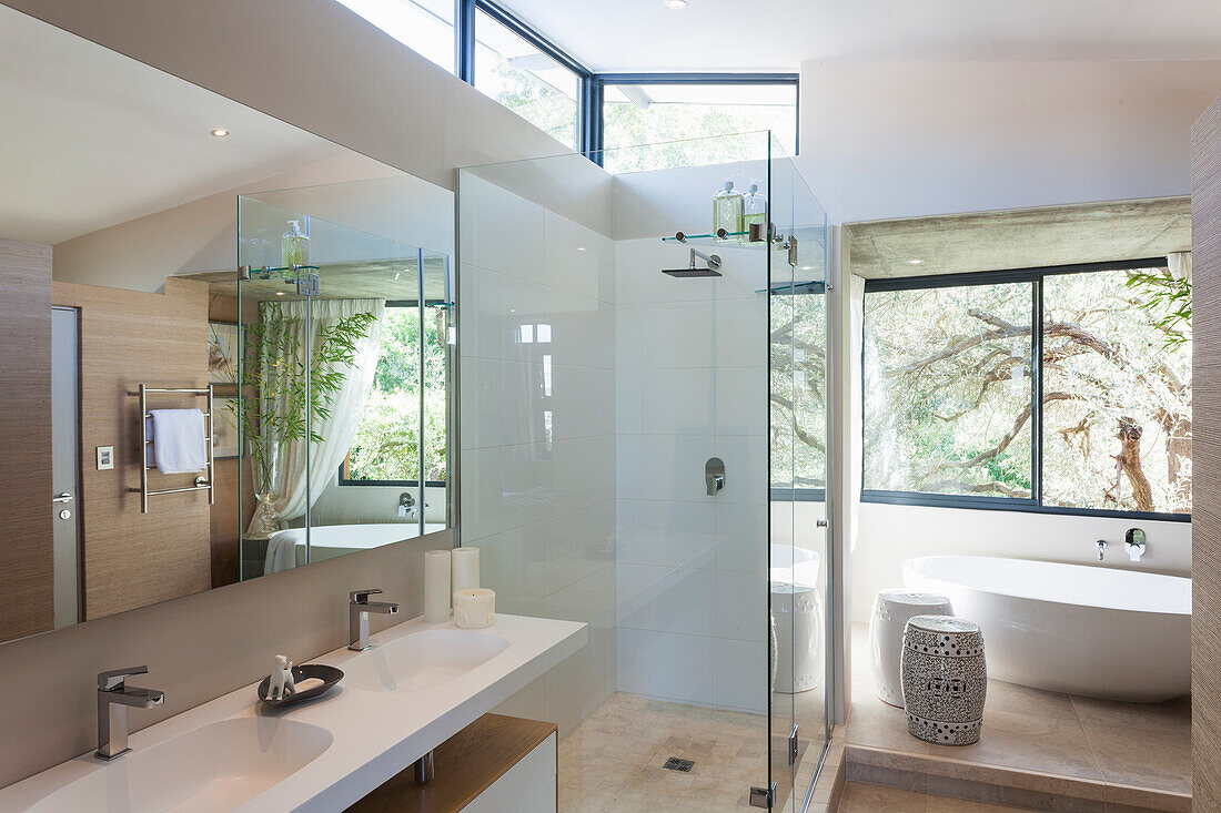 Modernes Badezimmer mit Glasdusche und freistehender Badewanne, Blick ins Grüne