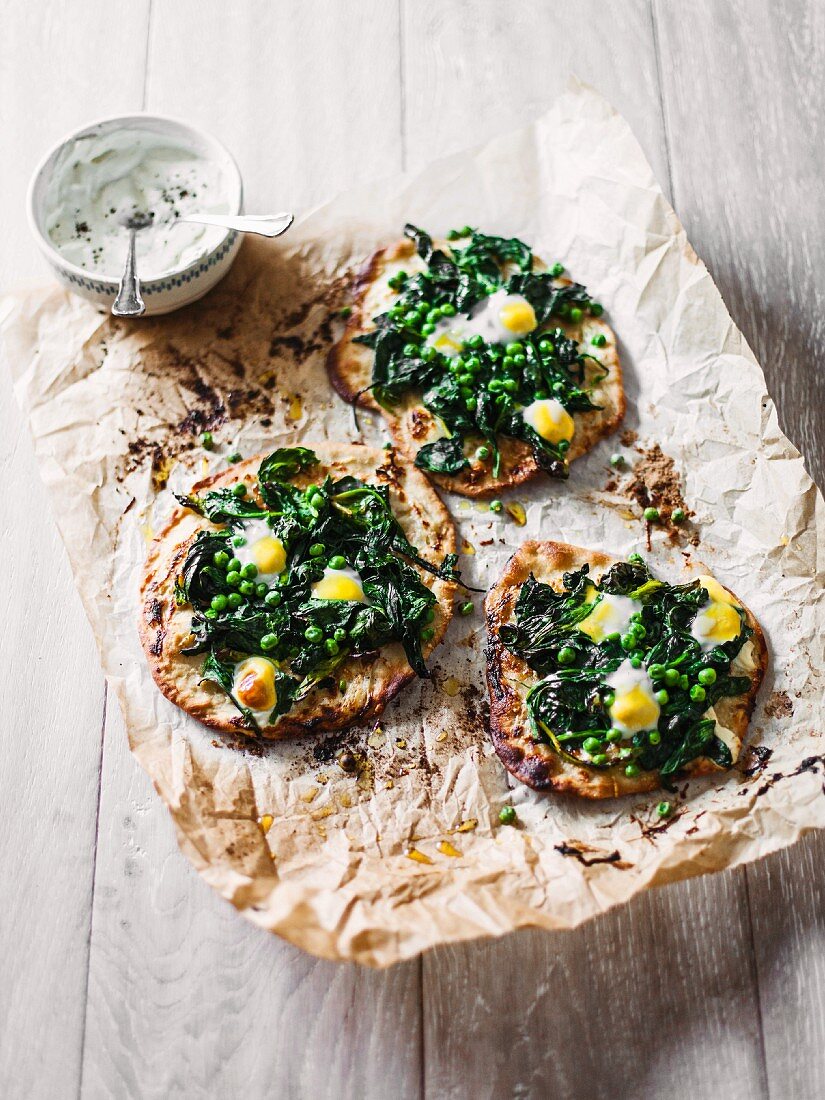 Mini pizzas with quails eggs, spinach and peas served with sour cream