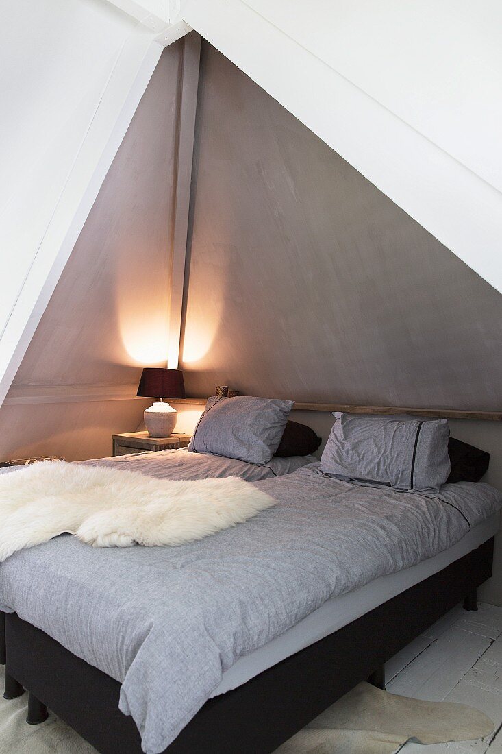 Sheepskin blanket on twin beds in bedroom alcove with table lamp in background