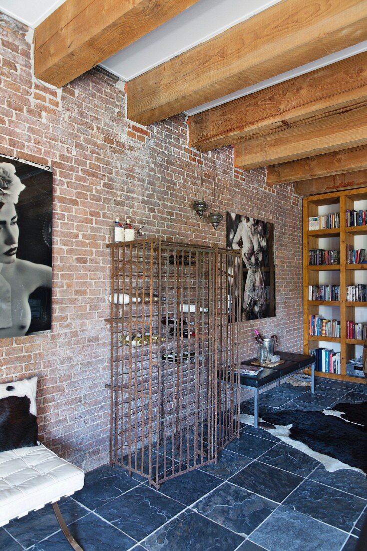 Loft-Wohnung mit Holzbalkendecke, Schieferboden und Weinregal aus Gitterstäben an Backsteinwand