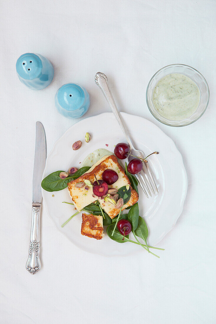 Halloumi with cherry and spinach salad and creamy pesto dressing
