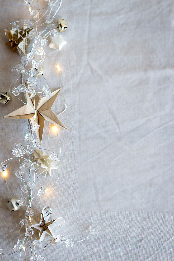 A string of fairy lights with origami stars and origami fir trees