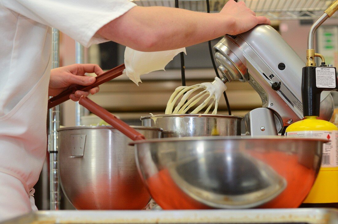 A baker using a kitchen machine for making cake