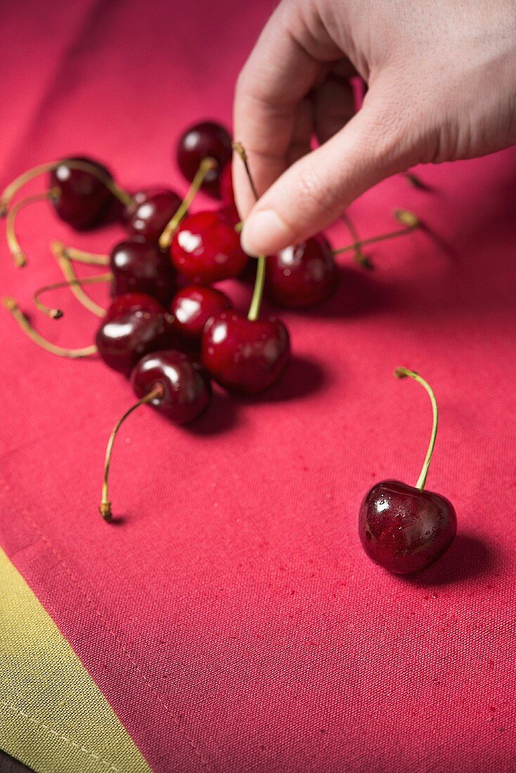 A hand reaching for cherries