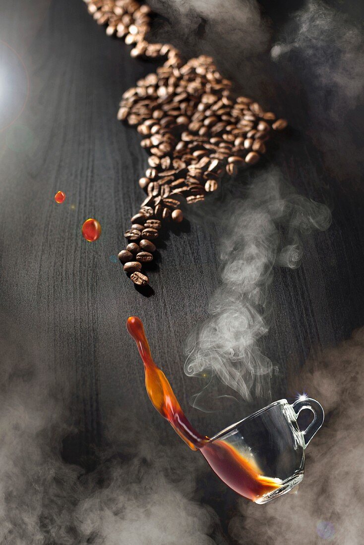 Dampfende Kaffeetasse schwebt über Tisch mit Kaffeebohnen