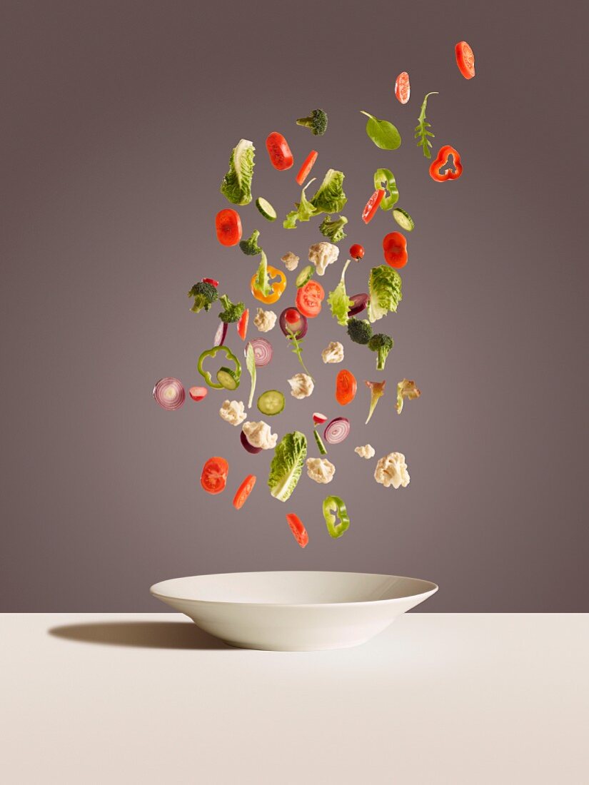 Slices of vegetables falling onto a white plate