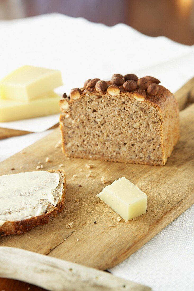 Mehrsaatenbrot mit Mandeln, angeschnitten mit Käse auf Holzbrett