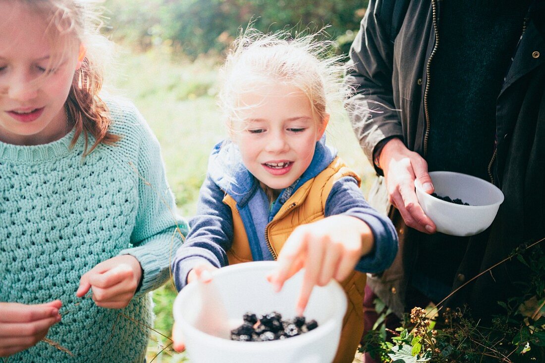 Two girls holding blackberries in a bowl