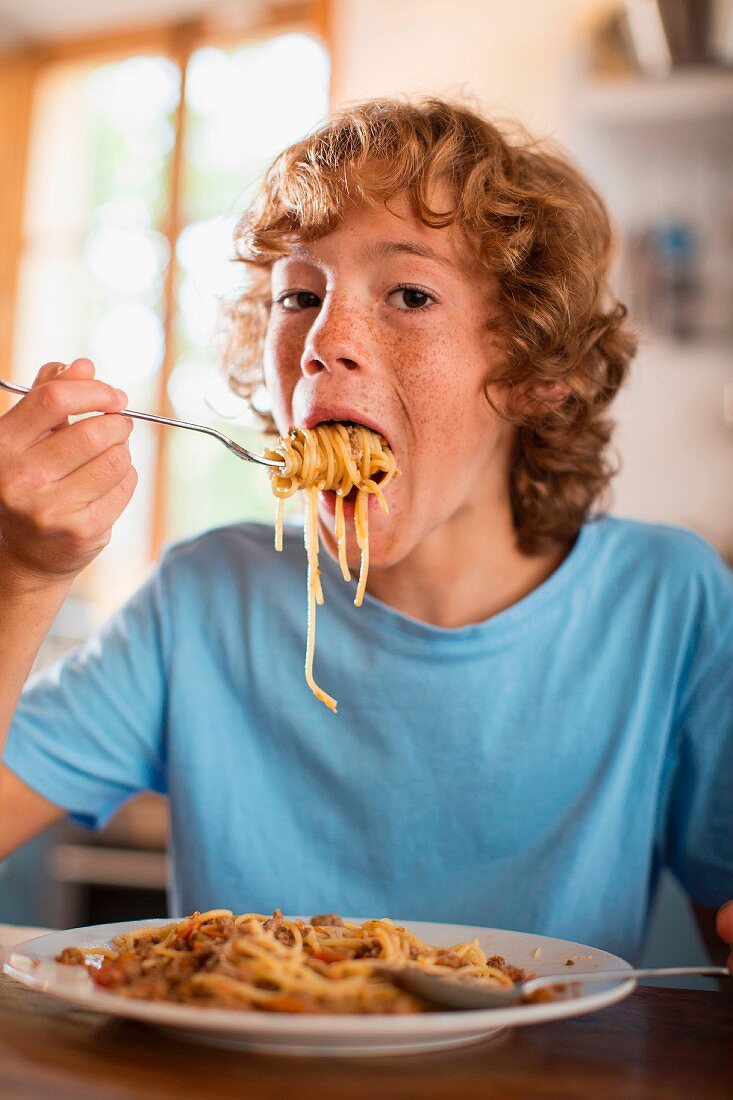 Teenager isst Spaghetti am Esstisch