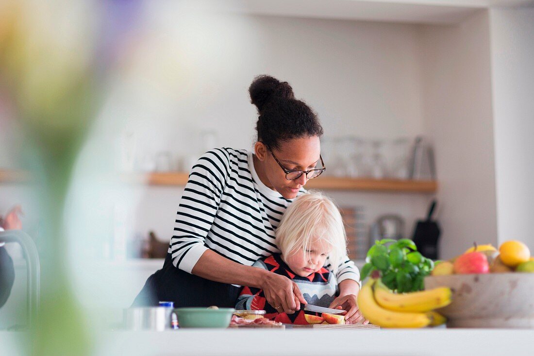 A mother and son cutting fruit together in the kitchen