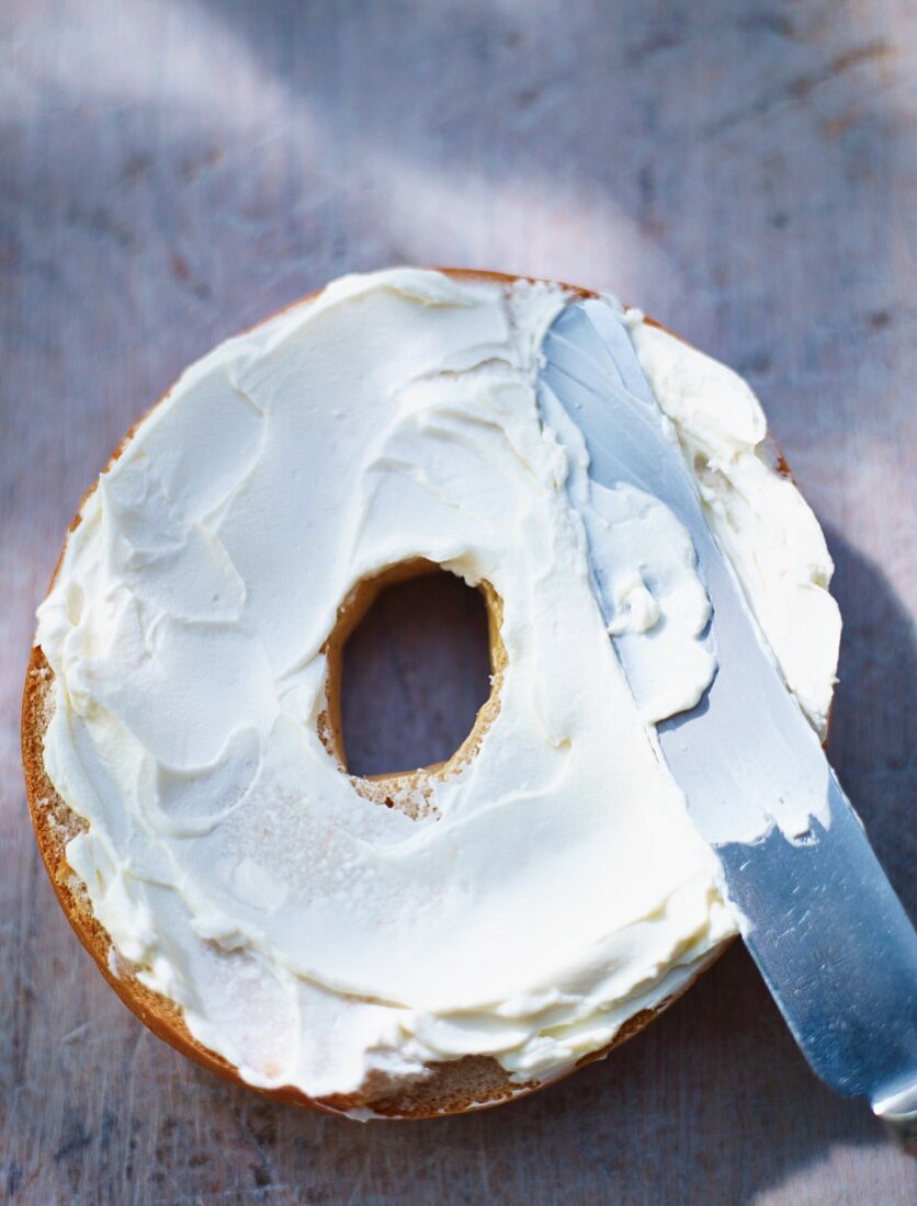 Half a bagel spread with cream cheese