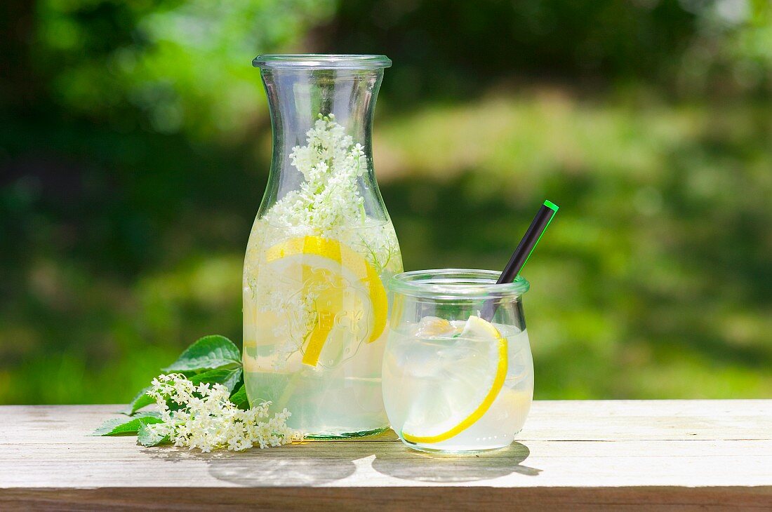 Zitronenlimonade mit Holunder auf Tisch im Freien