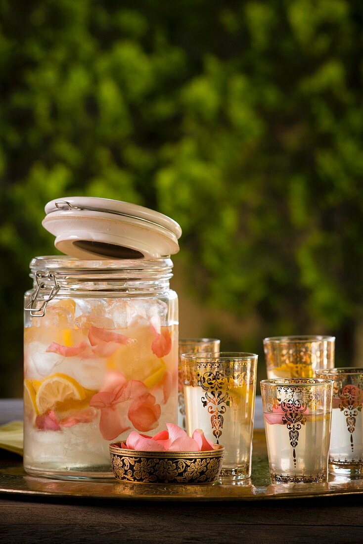 Rosenwasser-Limonade im Glas und orientalische Teegläser auf Tablett