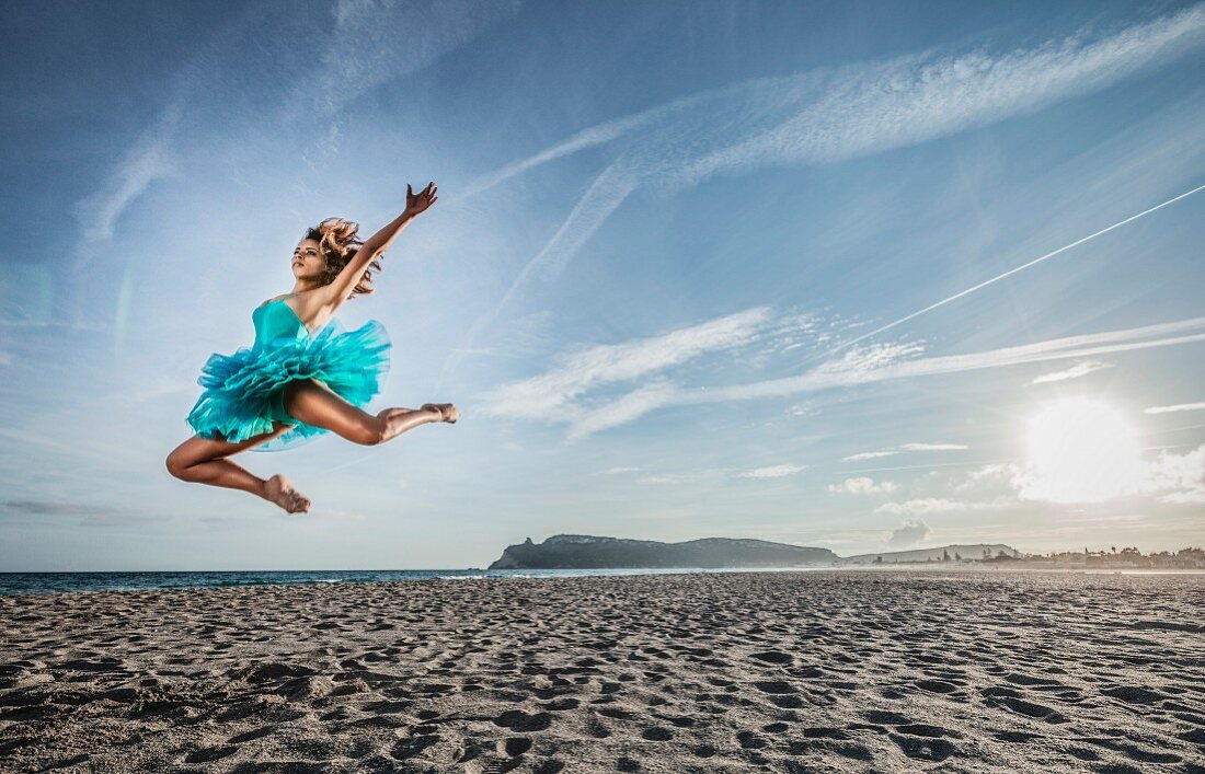 Junge Tänzerin am Strand beim Sprung durch die Luft