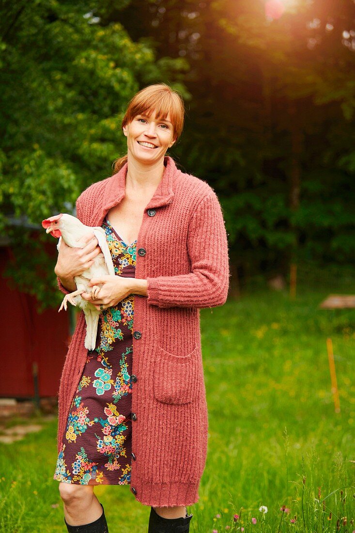 A woman holding a live chicken