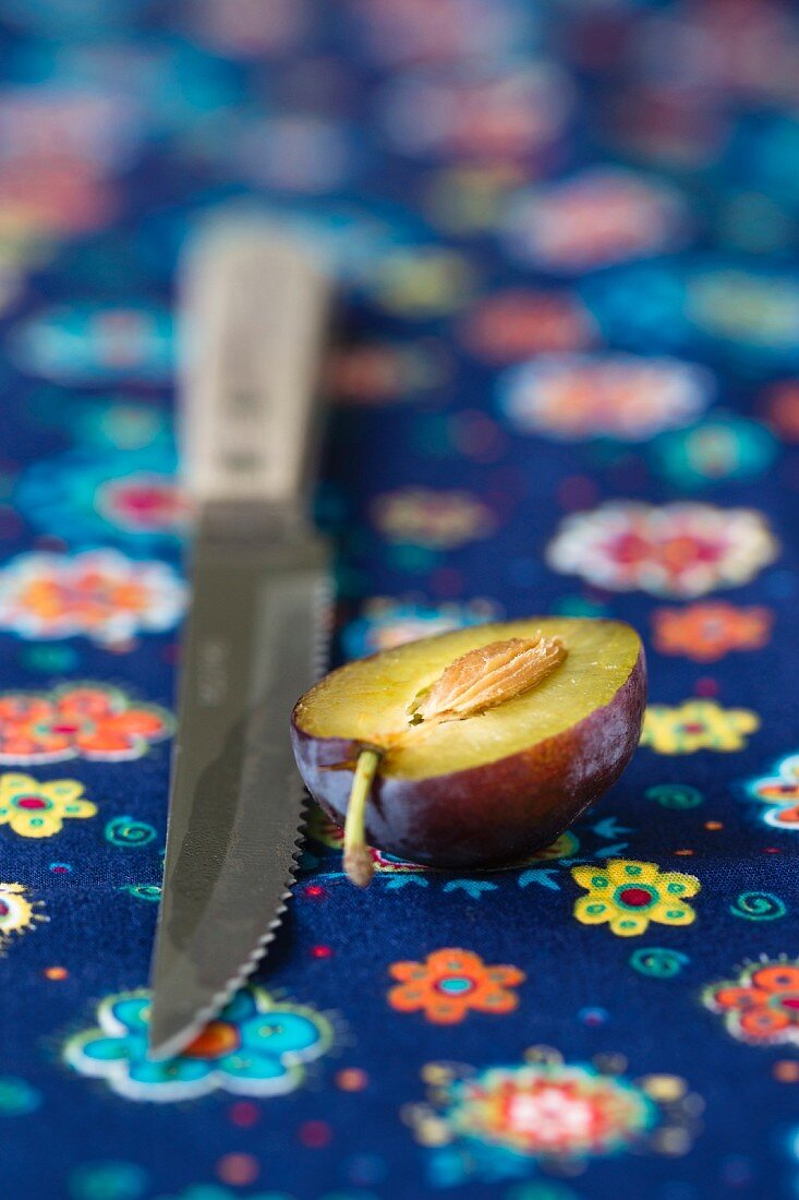 A halved damson and a knife