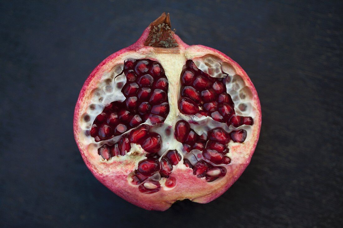 Half a pomegranate on a dark surface (close-up)