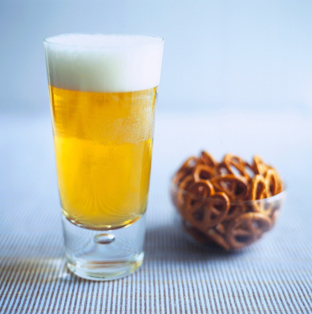 A glass of lager and a bowl of pretzels
