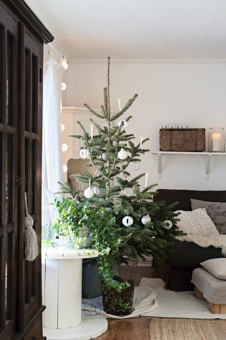 Simply decorated Christmas tree next to cable reel and armchair