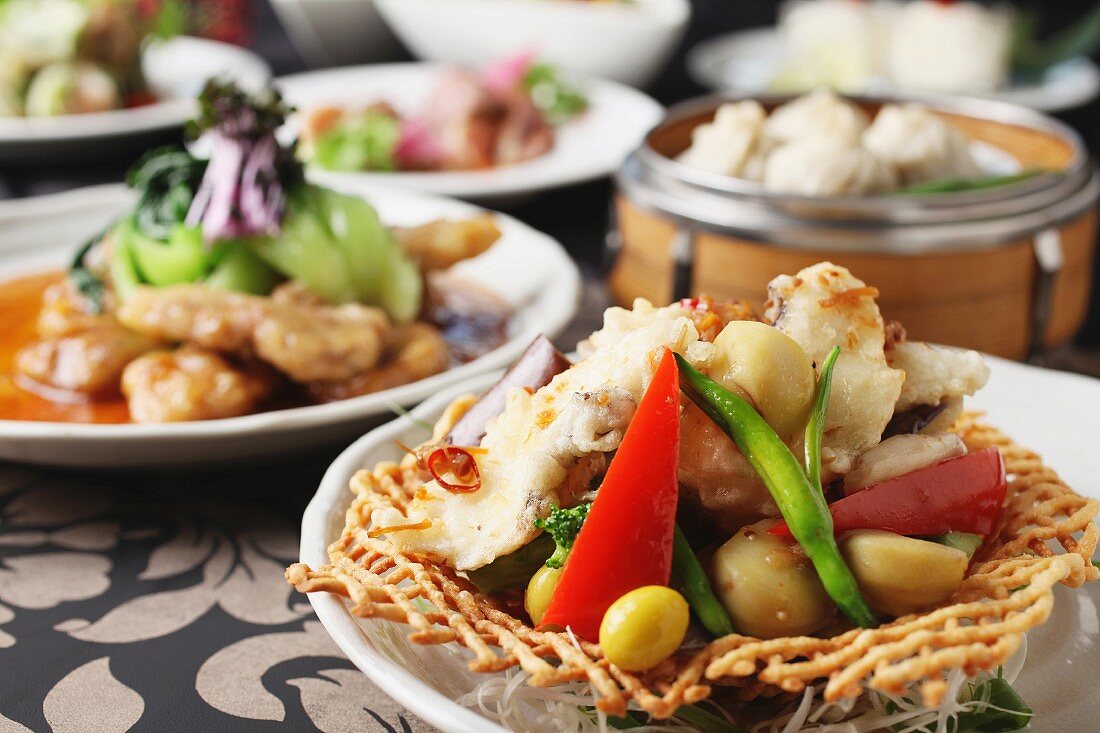Gegrilltes Hähnchenfleisch mit Gemüse, im Hintergrund Schweinefleisch mit Gemüse und Wan Tans