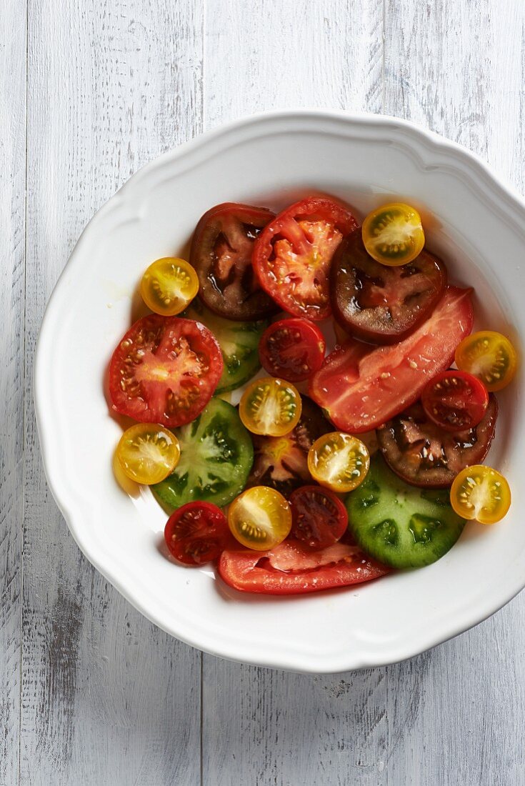 Verschiedenfarbige Tomatenscheiben in weißem Teller
