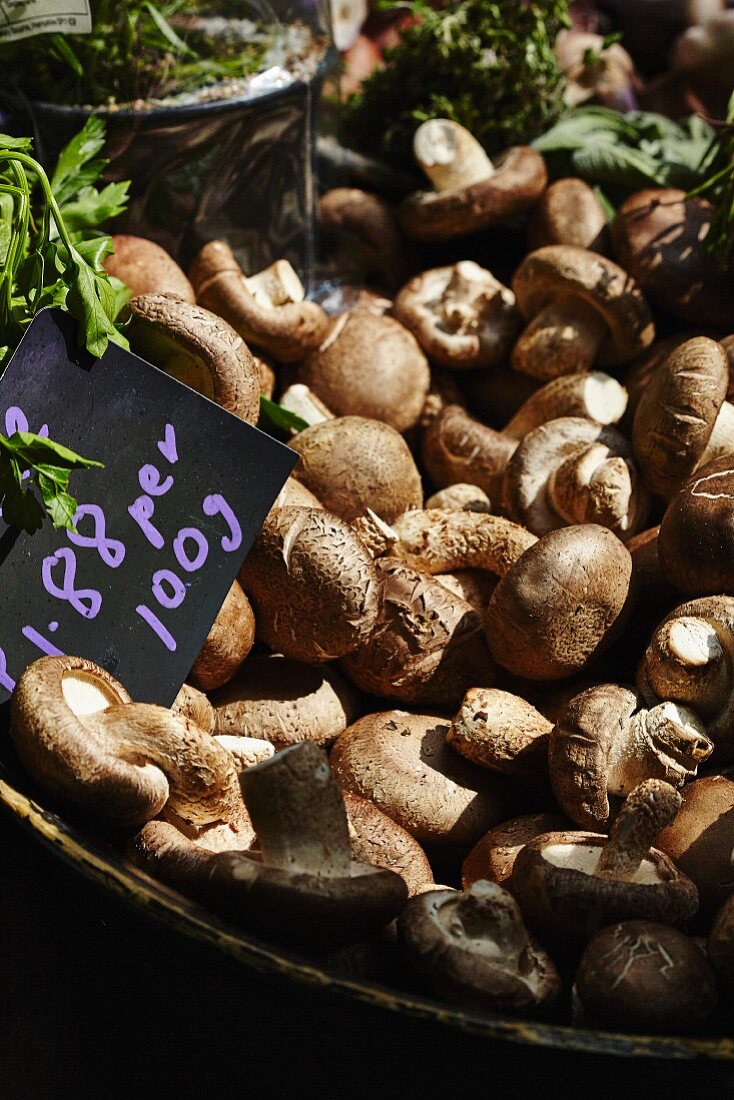 Brown mushrooms in a wooden bowl with a price label