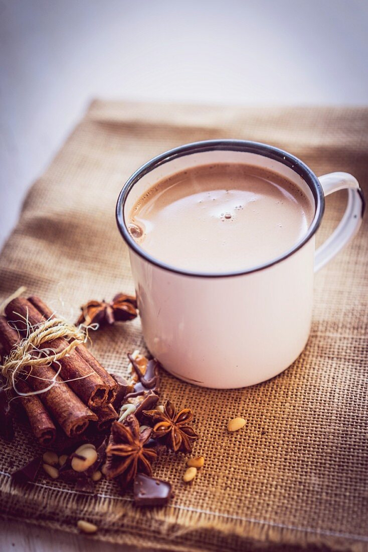 A mug of hot chocolate on a piece of jute with Christmas spices