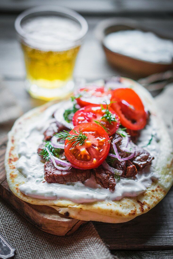 Pita bread topped with beef, cream cheese, tomatoes and onions
