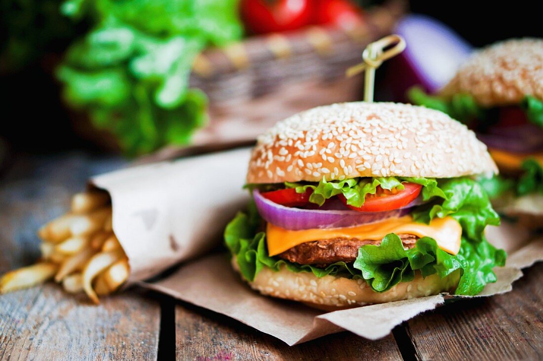 Cheeseburgers with onions, tomatoes, lettuce and chips