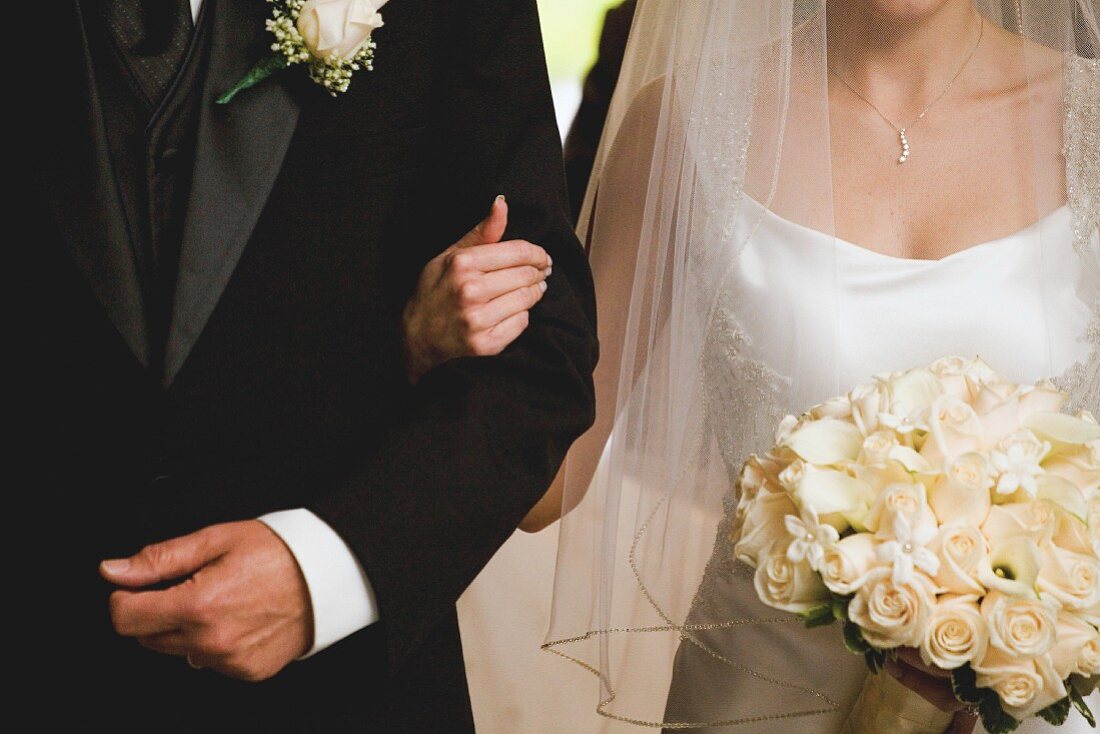 A bride and groom arm in arm (detail)
