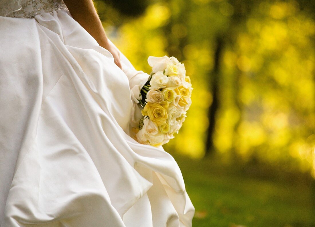 A bride wearing a white dress and holding a bouquet (detail)