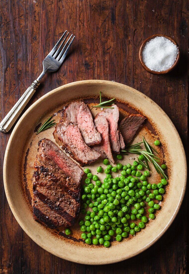 Sliced beef steak with peas and rosemary