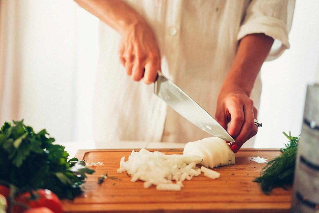 A woman chopping an onion in a kitchen