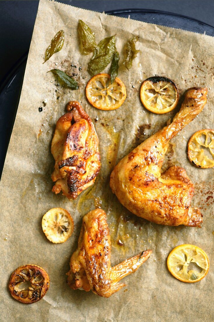 Chicken with lemon slices and sage on baking paper