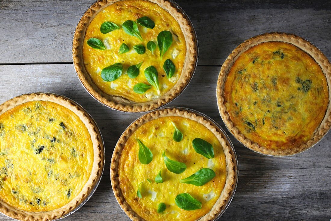 Four cheese quiches with herbs (seen from above)