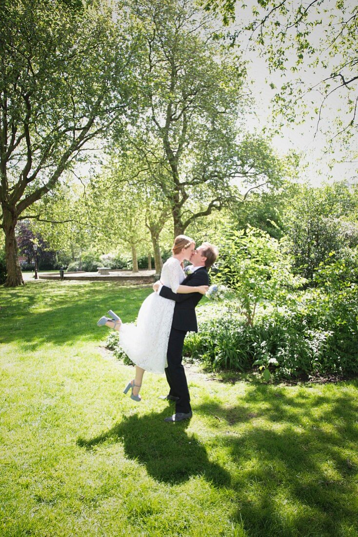 A young bride and groom kissing in a park