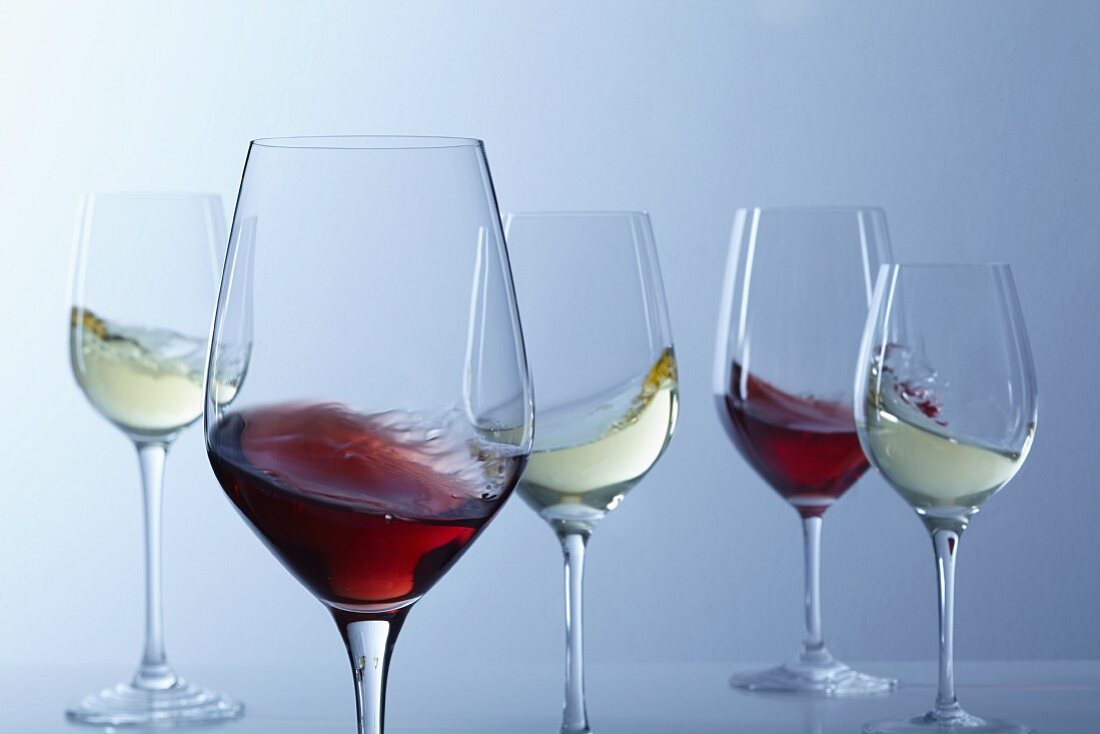 Red wine and white wine swirling in glasses