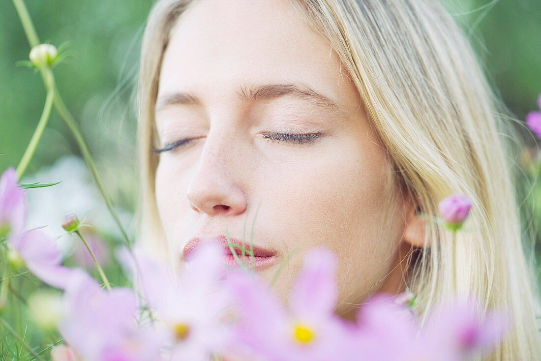 Portrait von junger Frau mit geschlossenen Augen auf Blumenwiese