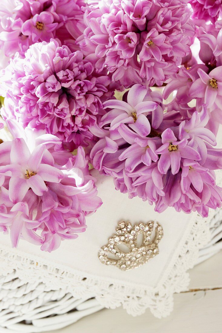 Pink hyacinth flowers, lace doily and rhinestone brooch