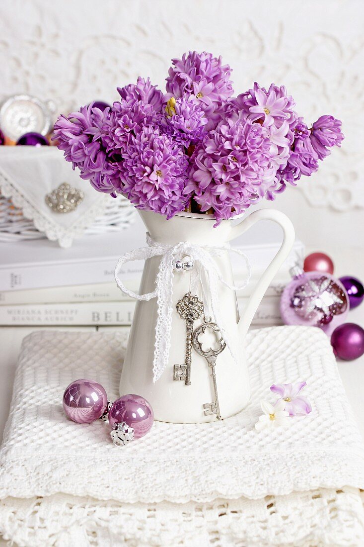 Purple hyacinths in vintage jug with baubles on lace doily