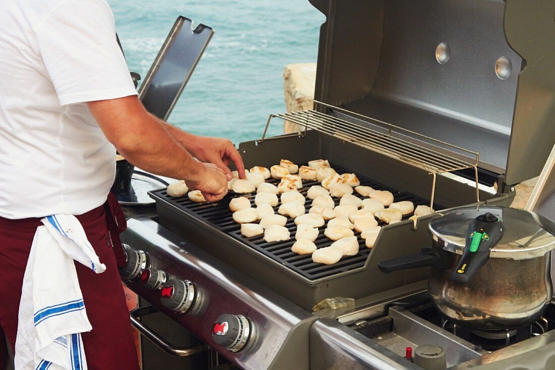 Koch grillt Jakobsmuscheln bei einer Hochzeitsfeier am Meer