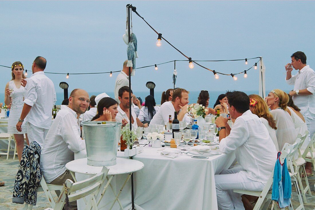 Hochzeitsgäste an einer Hochzeitstafel am Meer